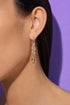 A close-up of a person's ear wearing a pair of gold earrings with a snake design.