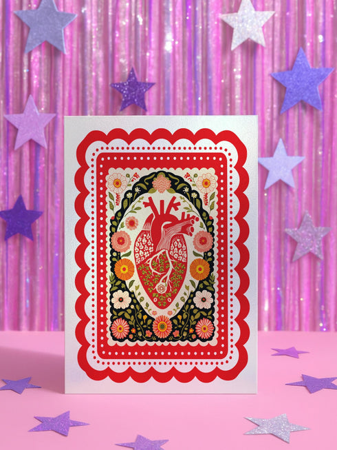 Realistic anatomical heart illustration printed in high contrast ink on a premium 5x7 inch shimmery pearlescent greeting card. The biological heart drawing features detailed arteries, veins, and ventricles, styled with a vintage medical or folk art aesthetic. The cardstock has a visible iridescent sheen. Blank inside valentine card shown with a white peel and seal envelope. Perfect for gothic decor, medical student gifts, cardiology nurse appreciation, and dark academia stationery collections.