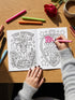 A 8.5 by 11 inch softcover coloring book titled The Feminist Rage Coloring Book For Cute Loud Unhinged Women. The black cover features vibrant pink and green typography, a fanged heart engulfed in flames, pink roses, and crescent moons. The back cover displays a heart pierced by a dagger and text reading Your feelings are valid your rage is too. Inside pages contain black and white line art with bold feminist quotes, floral borders, potions, coffins, and edgy witchy illustrations.