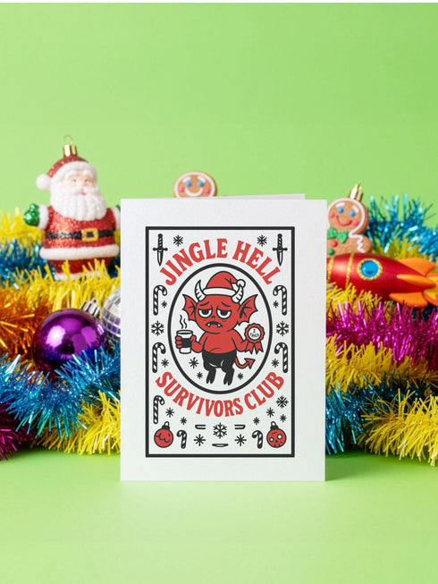 A 5x7 pearlescent shimmer folded greeting card featuring the Jingle Hell Survivors Club design. The front is a illustration of a grumpy red devil imp character, wearing a small Santa hat, holding a coffee cup, and a circular 'I Tried' merit badge. The overall aesthetic is maximalist dark humor and spooky cute. This anti-Christmas card is perfect for those needing relief from holiday stress. Inside text references surviving tolerable relatives, strong eggnog, and merciful hangovers.