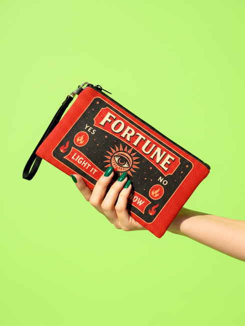 A rectangular red zippered pouch featuring a vintage-style tarot card design. The front displays the word FORTUNE in large beige capital letters. A central illustration shows a mystic eye emitting rays of light above a lit candle flame. The text YES and NO appears on the sides. A banner at the bottom reads LIGHT IT TO KNOW. The bag is crafted from red polyester with a linen-like woven texture, featuring a black zipper and a removable black nylon wrist strap. The interior is white.