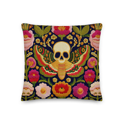 A square decorative throw pillow with a dark navy background and a linen-feel polyester texture. The design features a large, centrally-placed Death's Head hawkmoth with a detailed human skull marking on its thorax. The moth's wings are intricately patterned in shades of red, green, and gold. It is surrounded by a dense, symmetrical arrangement of colorful folk-art style flowers in vibrant shades of pink, red, and orange, with green leaves and vines. The print has a faux-embroidery appearance.