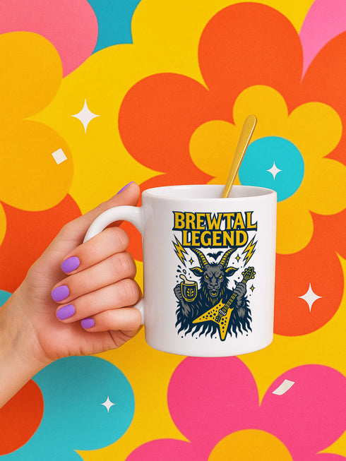 White ceramic 11oz coffee mug featuring a bold “Brewtal Legend” design with a heavy metal goat holding a yellow electric guitar and a beer stein, surrounded by lightning bolts. The graphic appears on both sides of the mug for left and right handers. Dishwasher and microwave safe. Perfect gift for punk, goth, and metalhead coffee or beer lovers.