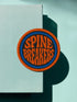 3-inch round embroidered iron-on patch made from a cotton–polyester blend; navy center with blue ring and orange outer ring; stacked orange text reads “SPINE BREAKERS”; merrowed border. Book club patch for paperback addicts, library tote flair, and literary merch collectors; makes a great gift for readers who annotate, dog-ear, and devour novels.