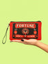 A rectangular red zippered pouch featuring a vintage-style tarot card design. The front displays the word FORTUNE in large beige capital letters. A central illustration shows a mystic eye emitting rays of light above a lit candle flame. The text YES and NO appears on the sides. A banner at the bottom reads LIGHT IT TO KNOW. The bag is crafted from red polyester with a linen-like woven texture, featuring a black zipper and a removable black nylon wrist strap. The interior is white.