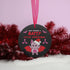 Round black metal Christmas ornament featuring cute pink bat with red wings wearing Santa hat, surrounded by pink bats and holly. Text reads "Have Yourself A Batty Little Christmas"