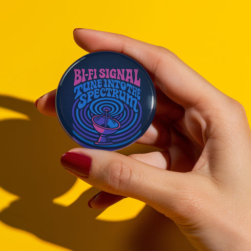 Round pinback button with glossy finish featuring the phrase “Bi-Fi Signal Tune Into the Spectrum” in pink and blue psychedelic lettering, with a satellite dish graphic, available in 2-inch and 3-inch sizes.