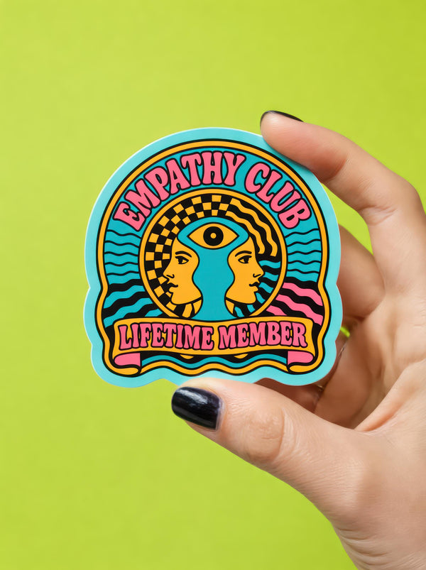 Retro Empathy Club Sticker: 70s Psychedelic Witchy Decal with Spiritual Third Eye for Laptop, Journal. Hand holding vivid sticker featuring “EMPATHY CLUB” text, psychedelic human profiles, third eye, wavy, checkerboard patterns. Ideal for empaths, spiritual seekers, and those loving retro vibes. Perfect mystical laptop decor or journal accessory. Available in matte, glitter, prismatic finishes. Enhances self-expression, great empath gift, not waterproof. Join Honey Dazed's universe of creative originality.
