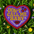 A heart-shaped embroidered patch with a thick red border and a vibrant purple background. In the center, the phrase "DON’T CALL ME BABY" is stitched in a bold, golden-yellow block font. The patch is decorated with small white sparkles, a pair of red cherries with a black musical note, a pair of red lips, and a grey thorny vine design below the text. The overall design has a rebellious, retro, punk aesthetic with a handmade, textured look.
