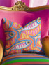 Flat printed square throw pillow cover featuring a faux embroidery texture. The vibrant maximalist design showcases stylized blue, pink, yellow, and white fish swimming in a dynamic, swirling pattern across a bright orange background. The artwork mimics heavy crewelwork yarn and stitching, but the material is a smooth 2D flat print. The pillow is shown as a finished square cover, designed to add bright, colorful eclectic fisherman aesthetic decor to any sofa or seating area.