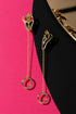 a pair of gold earrings with a unique design, hanging from chains against a contrasting background.
