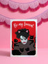 A vertical greeting card featuring a flat vector illustration of Robert Smith from The Cure against a vibrant red background. He has messy black hair, pale skin with smeared lipstick, and wears black cat ears. He is surrounded by four black cats with pink collars. White script text at the top reads "Be my Lovecat." The card is printed on shimmery pearlescent cardstock that catches the light. A high-quality alternative Valentine or anniversary card for goth music lovers and post-punk fans.