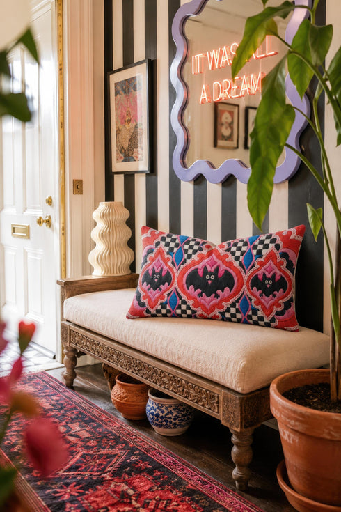 Rectangular 20x12 inch lumbar pillow cover in red featuring printed faux embroidery of three black bats with white eyes and pink noses, each framed in an ornate ogee medallion with pink flame stitch centers, black and white checkerboard accents, and cobalt blue diamonds. Whimsigoth damask bat design printed on both sides with a hidden zipper, crafted from soft linen look polyester for spooky maximalist home decor.