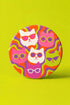 A close-up photograph of a glossy round ceramic coaster featuring a retro 70s psychedelic design. The artwork displays a cluster of six stylized cat face illustrations, each wearing a different pair of sunglasses including retro round and cat-eye shapes. The cats are colored in solid shades of white, hot pink, purple, and lime green. They are set against a vibrant background of wavy, swirling lines in bright orange, red, and purple. The top surface has a highly reflective clear glaze.
