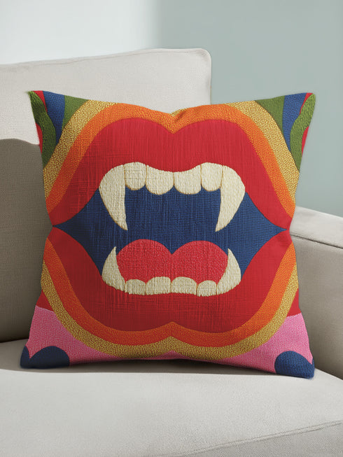 A colorful throw pillow with a graphic design of a pair of open, fanged mouths in red, blue, and yellow colors.