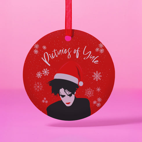 Round red metal Christmas ornament featuring Robert Smith silhouette in black with white Santa hat, red lips, and snowflake details. Text reads "Pictures of Yule" in white script.