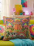 Description of a square throw pillow with a vibrant maximalist alien design. A central UFO with a large all-seeing eye hovers above a landscape with two rainbows, pink mountains, and green pine trees. A black and white spotted cow stands in the foreground. The design is a high-contrast palette of sky blue, magenta, hot pink, and meadow green. The pillow has a faux-embroidery 2D print finish on linen-feel fabric, framed by a yellow and pink scalloped floral border.