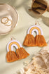 a pair of orange and white tassel earrings, a pair of sunglasses, and a ring on a light green surface.