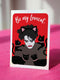 A vertical greeting card featuring a flat vector illustration of Robert Smith from The Cure against a vibrant red background. He has messy black hair, pale skin with smeared lipstick, and wears black cat ears. He is surrounded by four black cats with pink collars. White script text at the top reads "Be my Lovecat." The card is printed on shimmery pearlescent cardstock that catches the light. A high-quality alternative Valentine or anniversary card for goth music lovers and post-punk fans.