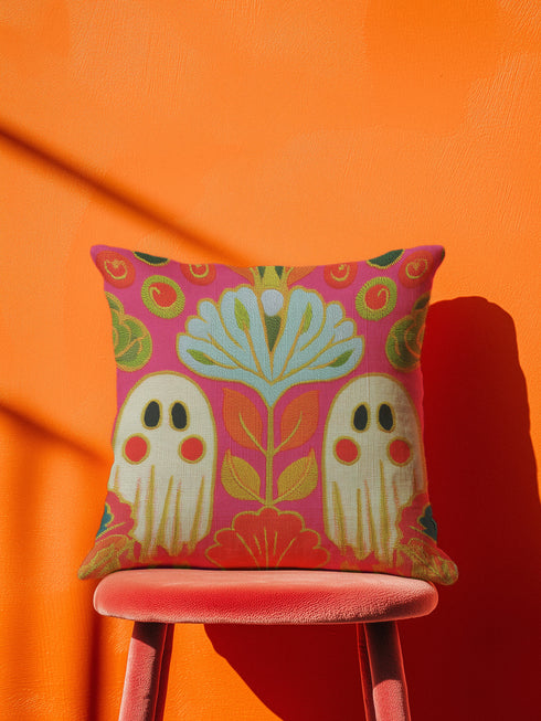 a vibrant, colorful pillow with a floral design, placed on a red chair against an orange background.
