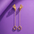 A pair of gold earrings with a chain and circular rings, displayed against a purple background.