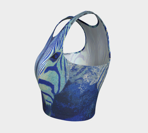 A women's sleeveless, high-neck crop top made from a performance spandex knit fabric. The top is designed with a body-hugging fit and features a striking, symmetrical digital graphic of a zebra's face. The intricate print uses shades of electric blue, cobalt, and navy, contrasted with a shimmering silver glitter effect that outlines the zebra's stripes and features. The psychedelic, futuristic design covers the entire front of the shirt.