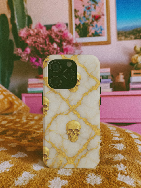 a smartphone case with a gold skull design on a white background.