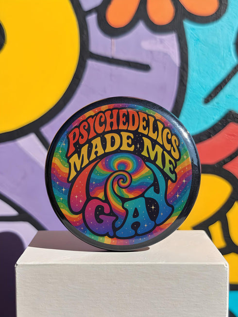 Round glossy pinback button measuring 2.25 inches featuring a vibrant rainbow psychedelic swirl with retro-style text that reads “Psychedelics Made Me Gay.” The background is a mix of rainbow waves and sparkles, with bold, colorful typography in orange, yellow, and blue. Made from durable tinplate with a safety pin backing, scratch-resistant mylar coating, and a high-gloss finish. Ideal for jackets, backpacks, or pride festival accessories.