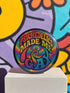 Round glossy pinback button measuring 2.25 inches featuring a vibrant rainbow psychedelic swirl with retro-style text that reads “Psychedelics Made Me Gay.” The background is a mix of rainbow waves and sparkles, with bold, colorful typography in orange, yellow, and blue. Made from durable tinplate with a safety pin backing, scratch-resistant mylar coating, and a high-gloss finish. Ideal for jackets, backpacks, or pride festival accessories.