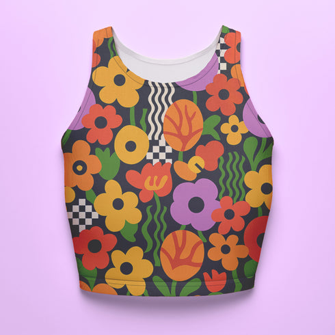 Vibrant retro cropped tank top featuring psychedelic 70s floral pattern with orange yellow purple flowers, black and white checkerboard accents, and wavy green lines on dark background. Body-hugging racerback design made from performance stretch fabric with moisture-wicking properties and UV protection. Perfect for festivals, raves, summer concerts, or bold streetwear styling.
