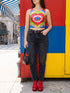 A sleeveless scoop neck crop top featuring a bold all-over printed design. The central graphic is a large bright red heart enclosing a scalloped pink flower shape and a blue evil eye motif in the middle. The background surrounds the heart with mirrored concentric wavy arches and scalloped borders in vibrant shades of lime green, pink, blue, and red. The fitted garment has a smooth athletic texture. Available in a standard matte performance knit or a sparkly silver glitter foil finish.