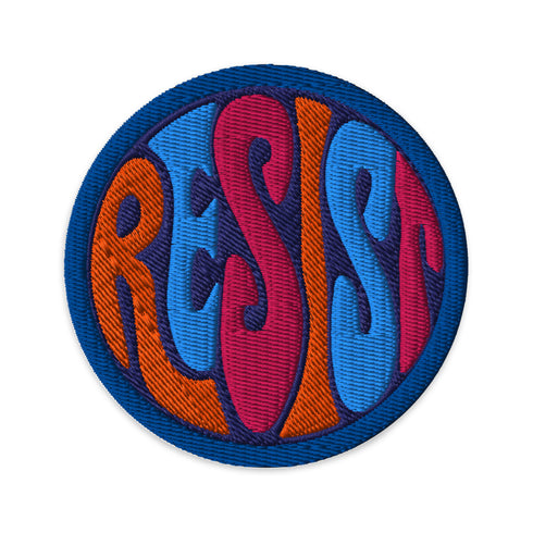 Round embroidered iron-on patch featuring "RESIST" text in bold flame design. Blue border surrounds navy background with orange, red, and blue flame-style lettering. 3x3 inch political activist patch with premium twill fabric construction, perfect for jackets, backpacks, and clothing customization. Anti-establishment protest accessory for resistance movements and political activism demonstrations.