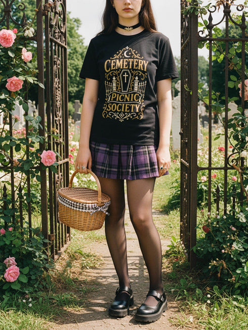 A black unisex crewneck graphic t-shirt featuring an ornate Victorian-inspired emblem printed on the chest in vintage gold and off-white. The centralized, symmetrical design showcases a classic coffin with a cross on the lid, flanked by wrought-iron cemetery gates. Beautiful scrollwork and decorative filigree flourishes surround the bold, retro serif text reading CEMETERY PICNIC SOCIETY. A crescent moon and stars sit at the top, completing this gothic memento mori graphic shirt.