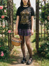 A black unisex crewneck graphic t-shirt featuring an ornate Victorian-inspired emblem printed on the chest in vintage gold and off-white. The centralized, symmetrical design showcases a classic coffin with a cross on the lid, flanked by wrought-iron cemetery gates. Beautiful scrollwork and decorative filigree flourishes surround the bold, retro serif text reading CEMETERY PICNIC SOCIETY. A crescent moon and stars sit at the top, completing this gothic memento mori graphic shirt.