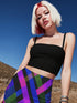 A young woman with blonde hair and red highlights is posing in a desert-like setting, wearing a black crop top and a colorful, patterned skirt.
