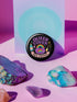 Glossy black pinback button with pastel artwork of a bubbling cauldron, rainbow, potion bottles, and tools. Text reads “Queer Coven, Hex Proud.”