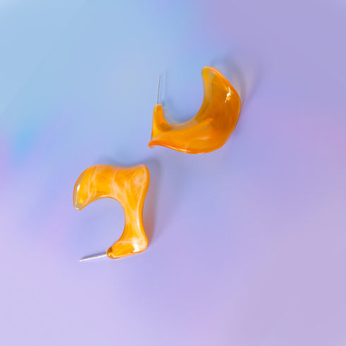 a pair of yellow earrings sitting on top of a table