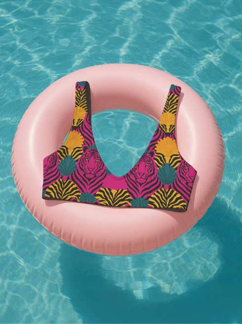 Tropical tiger print bikini top with bold pink, yellow, and teal psychedelic pattern. Scoop neck cut with wide straps, double-layered fabric, UPF 50+, and removable padding. Made from soft, stretchy recycled polyester and spandex.