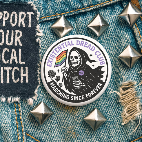Round pinback button featuring a bold black and white design of a skeleton reaper holding a rainbow pride flag and a drink, wearing a "RESIST" badge, surrounded by black roses, with "Existential Dread Club" in purple letters and "Marching Since Forever" in white. Glossy, metal button in 2" or 3" size.