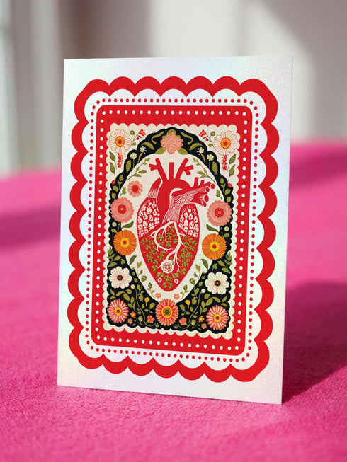 Realistic anatomical heart illustration printed in high contrast ink on a premium 5x7 inch shimmery pearlescent greeting card. The biological heart drawing features detailed arteries, veins, and ventricles, styled with a vintage medical or folk art aesthetic. The cardstock has a visible iridescent sheen. Blank inside valentine card shown with a white peel and seal envelope. Perfect for gothic decor, medical student gifts, cardiology nurse appreciation, and dark academia stationery collections.
