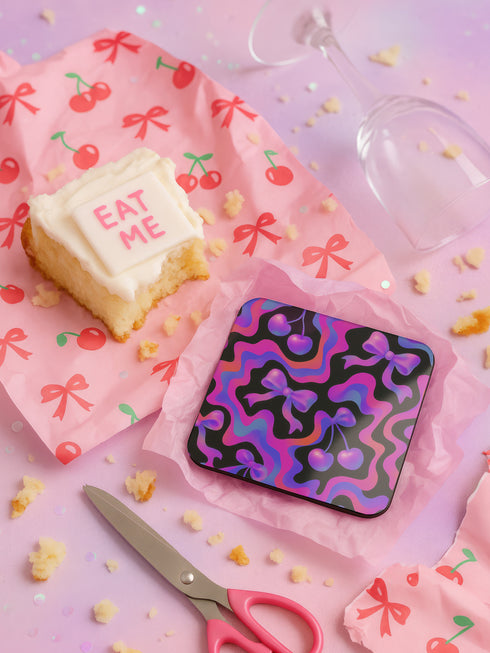 Square drink coaster featuring a bold Y2K-inspired pattern with gradient cherries and shiny pink bows on a black background with psychedelic pink, purple, and blue squiggle lines. Made from hardboard MDF with a non-slip cork backing and a high-gloss topcoat. Measures 3.74 by 3.74 inches. Water-repellent and heat-resistant, ideal for pastel goth, coquette, maximalist, and dopamine decor themes.