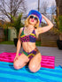 Colorblock animal print bikini top with neon pink, orange, green, purple, and blue abstract pattern. Scoop neck cut with wide straps, removable padding, double-layered fabric, UPF 50+, and made from soft, stretchy recycled polyester-spandex blend.