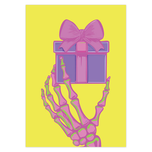 Birthday card with vibrant yellow background. A pink and green skeletal hand holds a purple and pink gift box with large pink bow. The illustration blends festive and spooky elements, creating a playful Halloween-meets-birthday aesthetic. The stylized, colorful design uses contrasting bright colors for a eye-catching effect. Inside message reads: 'Unwrap the Magic. Embrace the Spook. It's Your Day to Shine!' - combining celebratory spirit with a touch of the macabre for a unique birthday greeting.