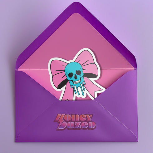 Pastel goth skull bow sticker with a blue skull and pink bow, perfect for creepy cute and punk lovers. Available in Prism, Gem, and Glitter finishes. Handmade in Austin, Texas.