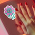 Trippy eyeball flower sticker in pastel pink and green, ideal for quirky and weirdcore enthusiasts. Available in Prism, Gem, and Glitter finishes. Handmade in Austin, Texas.