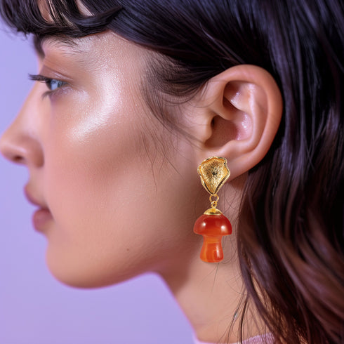 Handmade earrings featuring red agate mushroom-shaped drops with gold-plated caps, suspended from textured gold studs, showcasing unique cottagecore and boho aesthetic.