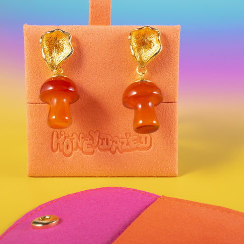 Handmade earrings featuring red agate mushroom-shaped drops with gold-plated caps, suspended from textured gold studs, showcasing unique cottagecore and boho aesthetic.