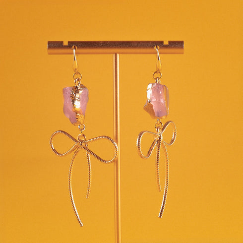 Earrings featuring pink rose quartz stones with 14k gold-plated brass bow designs, offering a sweet and sophisticated touch.