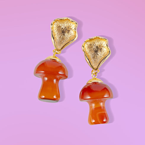 Handmade earrings featuring red agate mushroom-shaped drops with gold-plated caps, suspended from textured gold studs, showcasing unique cottagecore and boho aesthetic.