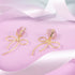 Earrings featuring pink rose quartz stones with 14k gold-plated brass bow designs, offering a sweet and sophisticated touch.